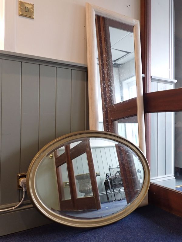 A GILT FRAMED OVAL WALL MIRROR