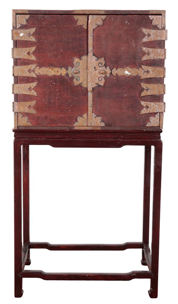 A CHINESE RED LEATHER AND GILT METAL MOUNTED CABINET ON STAND