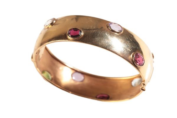 AN 18K GOLD GEM SET BANGLE