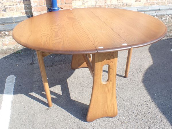 AN ERCOL STAINED ELM OVAL DROP-LEAF DINING TABLE