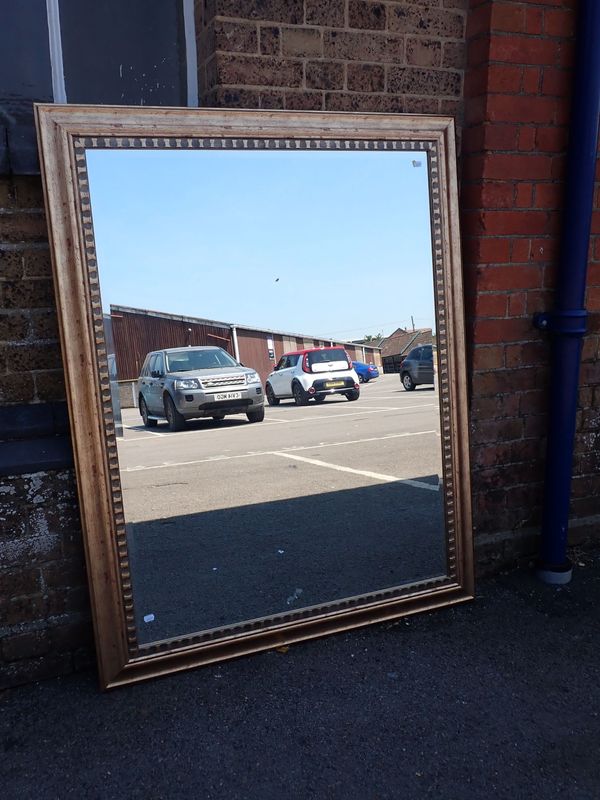 A MODERN GILT-FRAMED WALL MIRROR