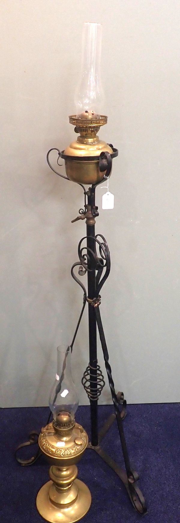 A BRASS OIL LAMP ON A WROUGHT IRON STAND
