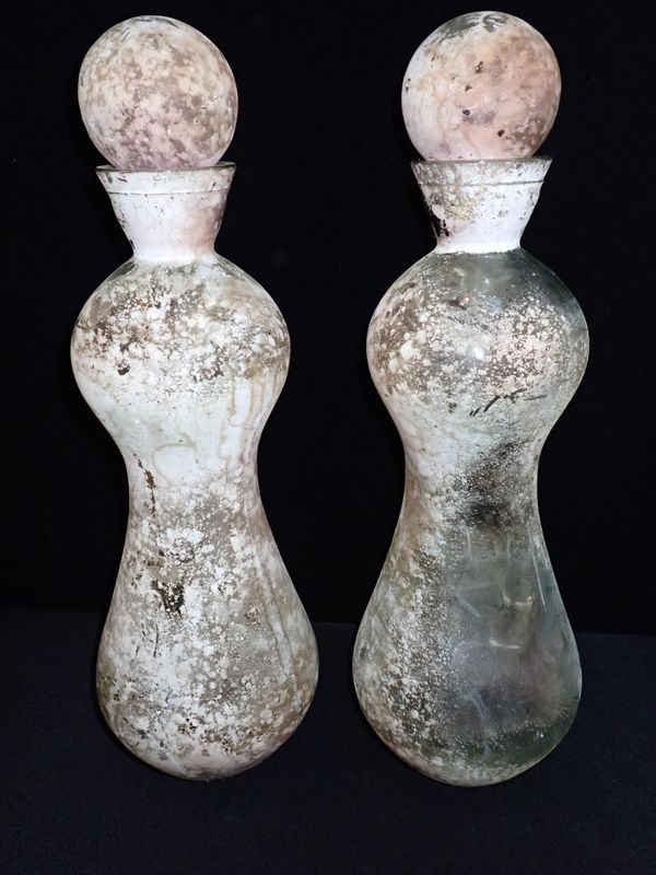 A PAIR OF PATINATED GLASS BOTTLES