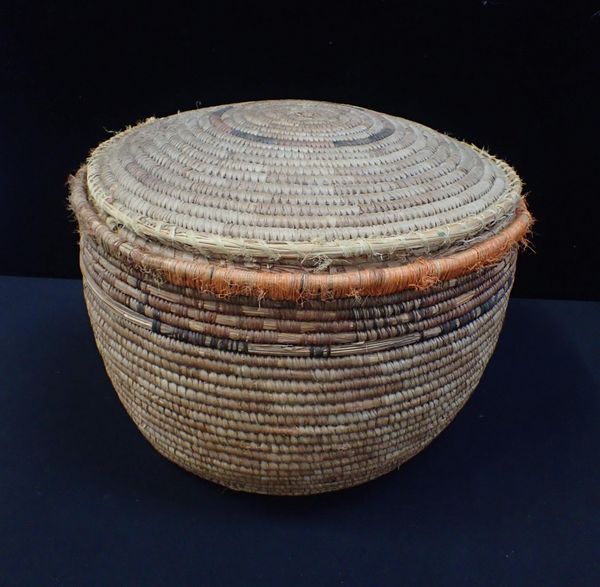 AN AFRICAN WOVEN BASKET WITH LID