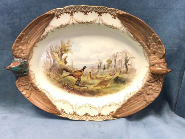A large oval Royal Worcester ashet embossed with pheasant handles and wings, the panel decorated with pheasants in landscape framed by floral garlands. (17.75in)