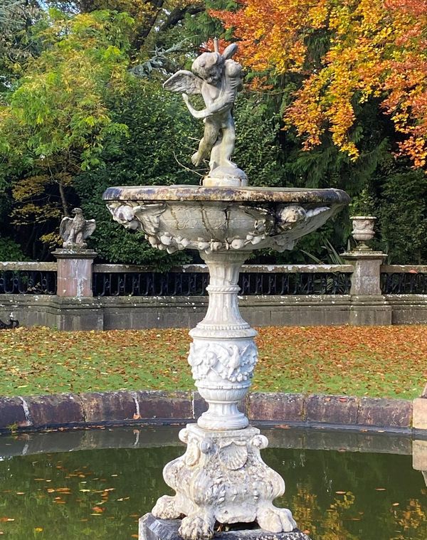A carved white marble fountain Italian, circa 1900 surmounted by a lead fountain figure of a cherub after Verrocchio 185cm high by 114cm...