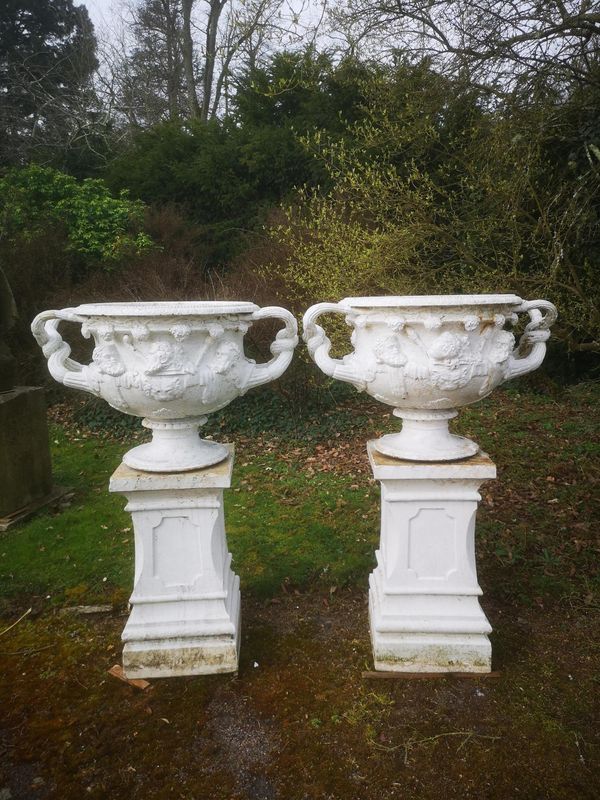 After the Antique: A pair of cast iron Handyside Foundry Warwick vases 2nd half 19th century on associated stoneware bases square bases to urns...