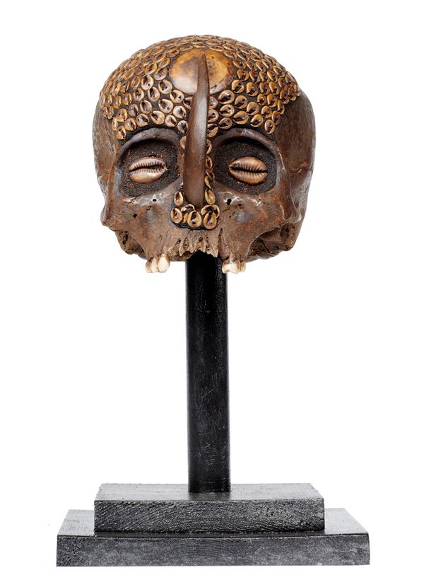 A Dayak tribe human skull on stand 35cm high overall
