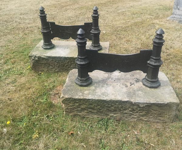 A pair of substantial cast iron boot scrapers on Cotswold stone bases mid 19th century 58cm high by 72cm long