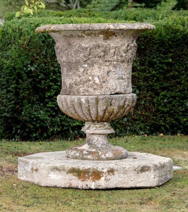 A substantial carved Cotswold stone urn 18th century on associated octagonal carved stone plinth 130cm high by 100cm diameter