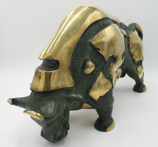 A gilt and patinated bronze model of a Bull 2nd half 20th century with stylised features  overall 32cm high by 56cm long by 15cm deep