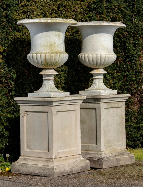 ‡ A pair of carved white marble urns Italian, late 19th century 86cm high, on later composition stone pedestals 163cm high overall 