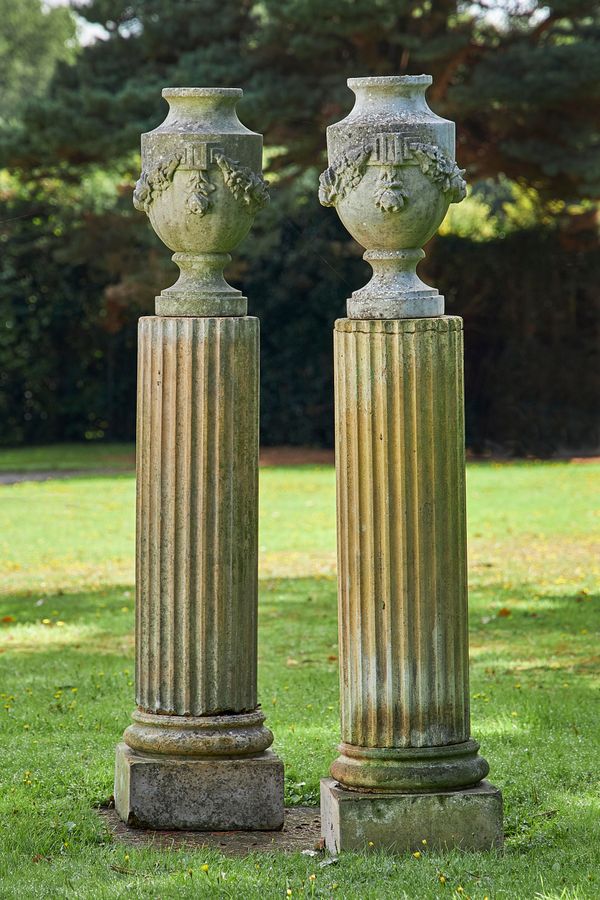 A pair of carved white marble urns late 19th century on later composition stone column pedestals the urns 50cm high; 166cm high overall