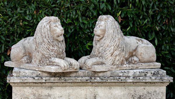 A pair of carved limestone reclining lions mid 20th century 65cm high by 100cm long