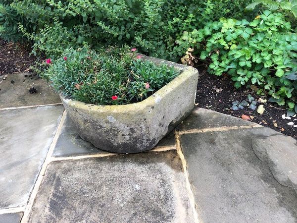 A carved stone trough 27cm high by 53cm wide by 61cm long (Flowers not included)