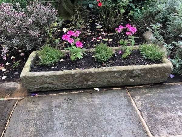 A carved stone trough 20cm high by 38cm wide by 112cm long (Flowers not included)