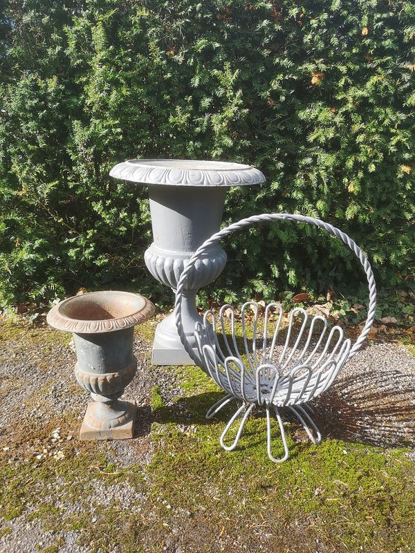 A cast iron urn 20th century 66cm high, a similar smaller urn, 32cm high and a wrought iron basket