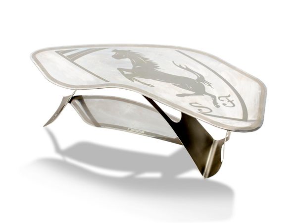 A polished steel Ferrari coffee table the top etched with a Ferrari style horse and initialled SF, the lower tier stamped In Omaggio al mio amico,...