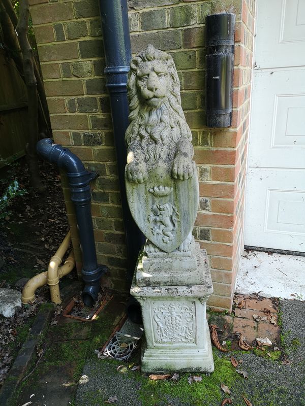 A pair of composition stone armorial lions on pedestals