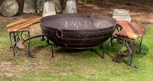 † A large wrought iron kadai modern 132cm diameter, together with a pair of curved wrought iron and wooden benches en suite 
