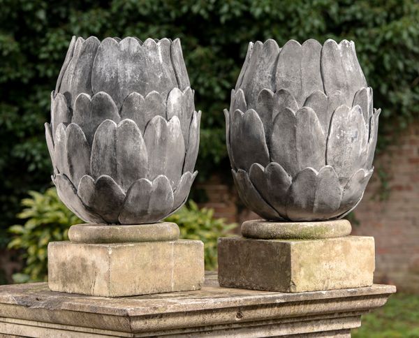 † A pair of lead artichoke finials modern on composition stone bases 66cm high