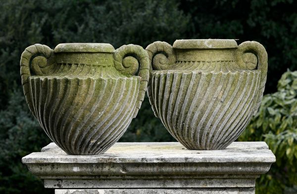 † A pair of carved sandstone wrythen fluted two handled urns modern 42cm high 