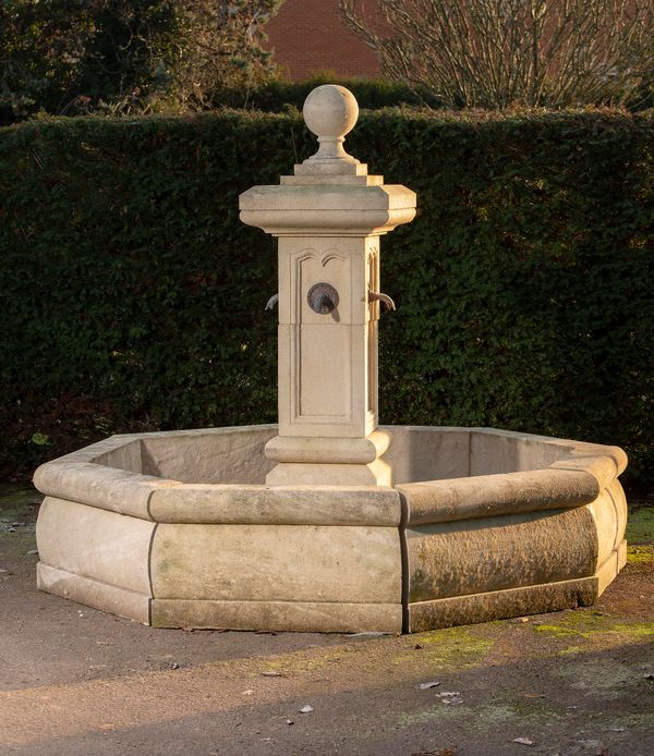 A carved limestone fountain and surround French, modern plumbed with four lead spouts 200cm high, the octagonal surround 50cm high by 230cm wide