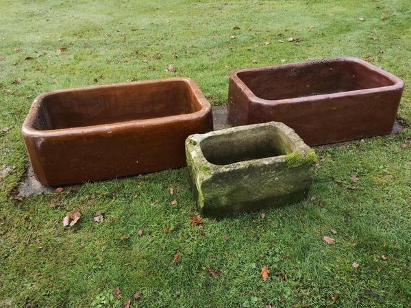 A pair of glazed earthenware troughs with makers stamp 25cm high by 72cm wide by 46cm deep, together with a smaller stone trough  23cm high by 40cm...