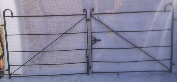 A pair of wrought iron gates late 19th century 120cm high by 280cm wide, together with a pair of wrought iron panels with similar hooped tops, each...