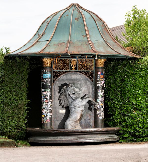 A circular double sided bronze and cast iron fountain with bronze horses on either side  the columns flanking the pool still have the stickers put on...