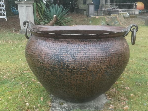 † A large beaten copper pot with ring handles