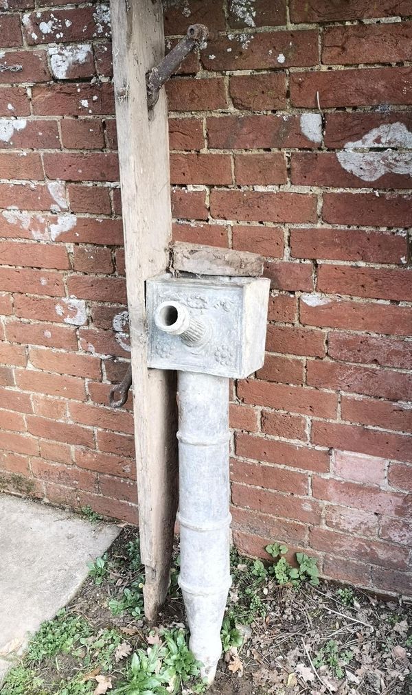 A Georgian lead pump head late 18th/early 19th century with wooden back plate and iron handle the pump head 88cm high