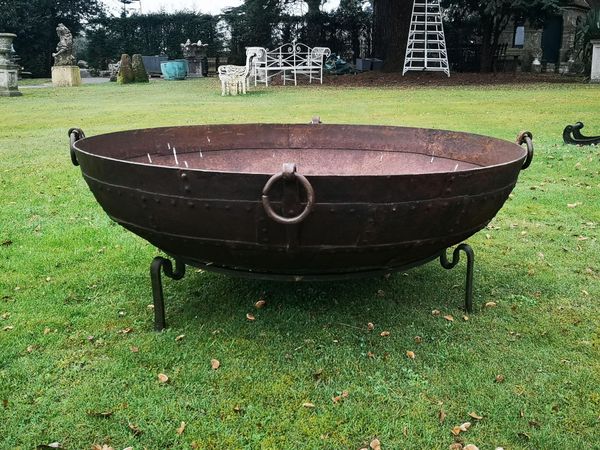 † A riveted wrought iron kadai Indian, 20th century on later wrought iron stand 130cm diameter