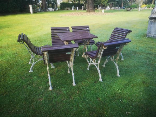 A suite of cast iron and wooden furniture by Benito modern each piece stamped with maker‘s plaque the table 79cm square