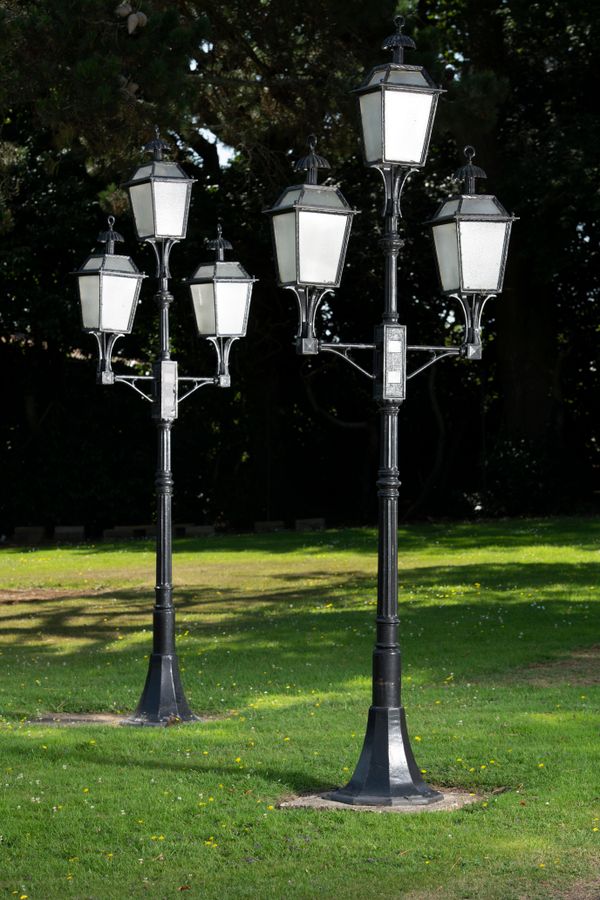 A pair of cast aluminium standing lamps  each with three lights 305cm high
