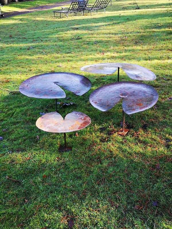 A graduated set of four sheet iron lilies with iron supports the largest 90cm diameter