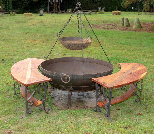 † A wrought iron Kadai of riveted construction Indian, modern  on wrought iron stand together with a tripod hanging cooking bowl and two wooden and...
