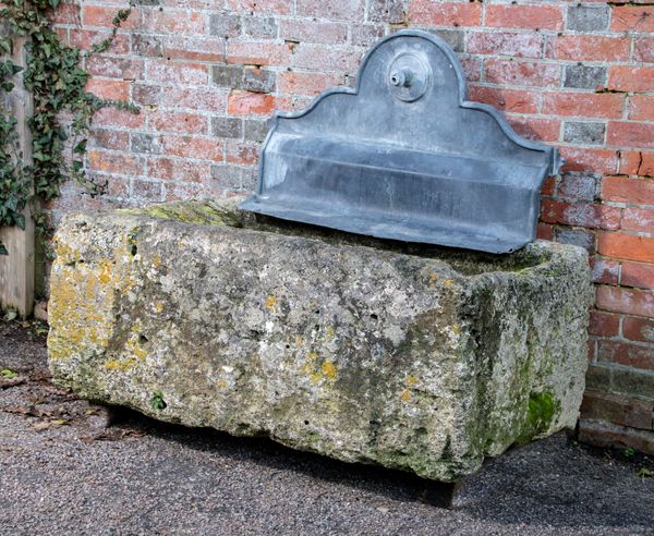 A carved stone trough 48cm high by 118cm long by 80cm deep surmounted by a lead fountain plate, 88cm wide