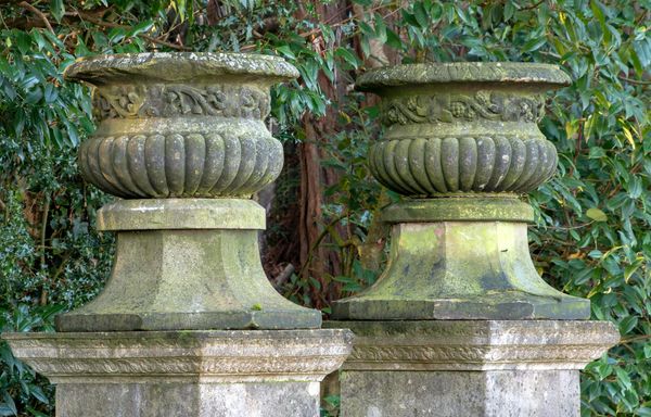 A pair of Victorian carved sandstone urns circa 1870 on associated tapering octagonal bases 74cm high