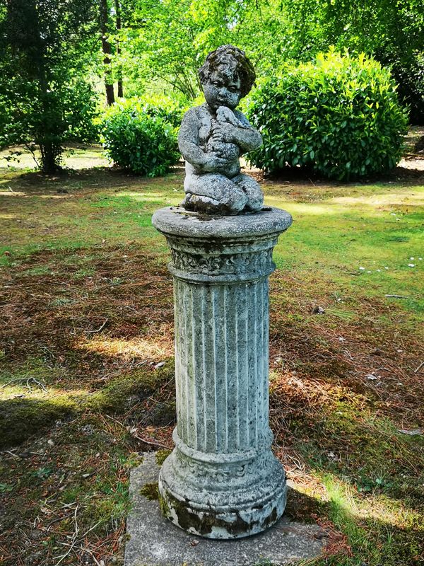 A composition stone figure of a child holding a rabbit on fluted column pedestal 2nd half 20th century 132cm high