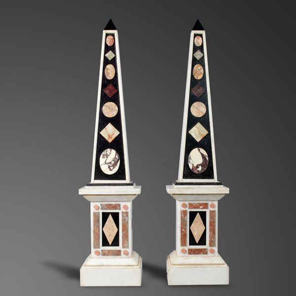 A pair of white and black marble obelisks on pedestals modern set with specimen marbles 190cm high