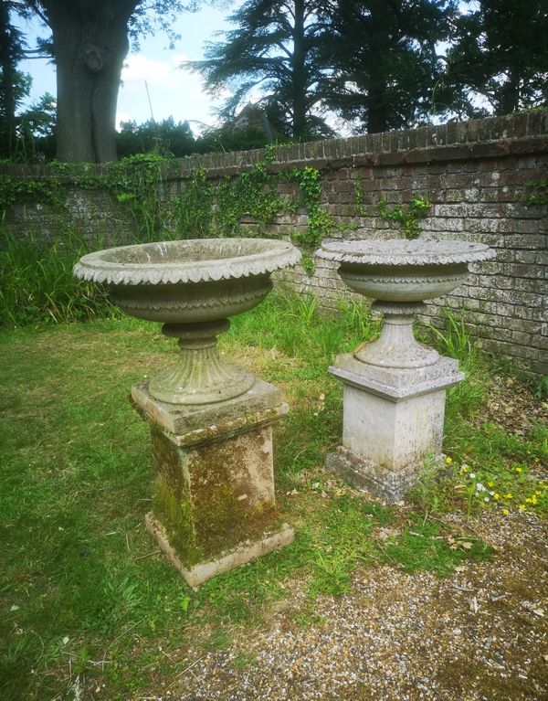 †A pair of carved sandstone urns on pedestals modern 92cm high, 61cm diameter 