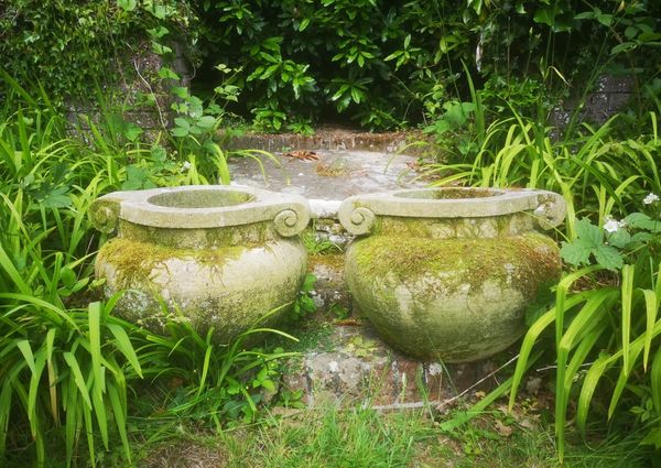 †A pair of carved sandstone Compton scroll pot style urns modern 44cm high, 61cm diameter 