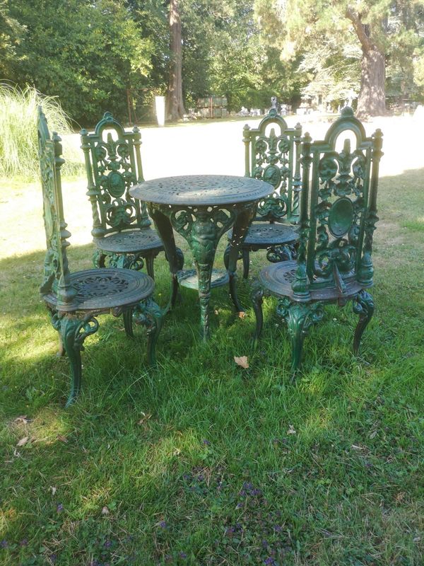 A set of four cast iron chairs with table en suite modern table 59cm diameter