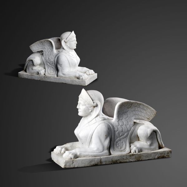 A pair of carved marble reclining sphinx last quarter 20th century 50cm high by 76cm long