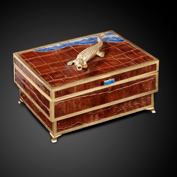 † An impressive humidor by Glyn Lockett applied with crocodile skin and gilt mounts the top surmounted with a crocodile with sapphire eyes next to an...