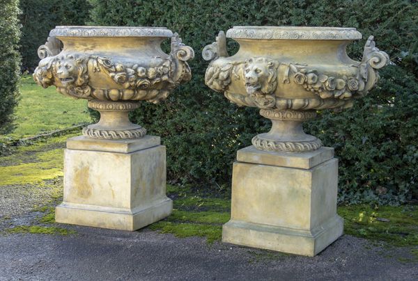 A pair of composition stone urns on pedestals