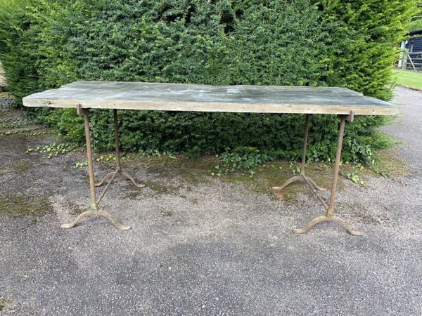 A rectangular slate table on iron trestle supports