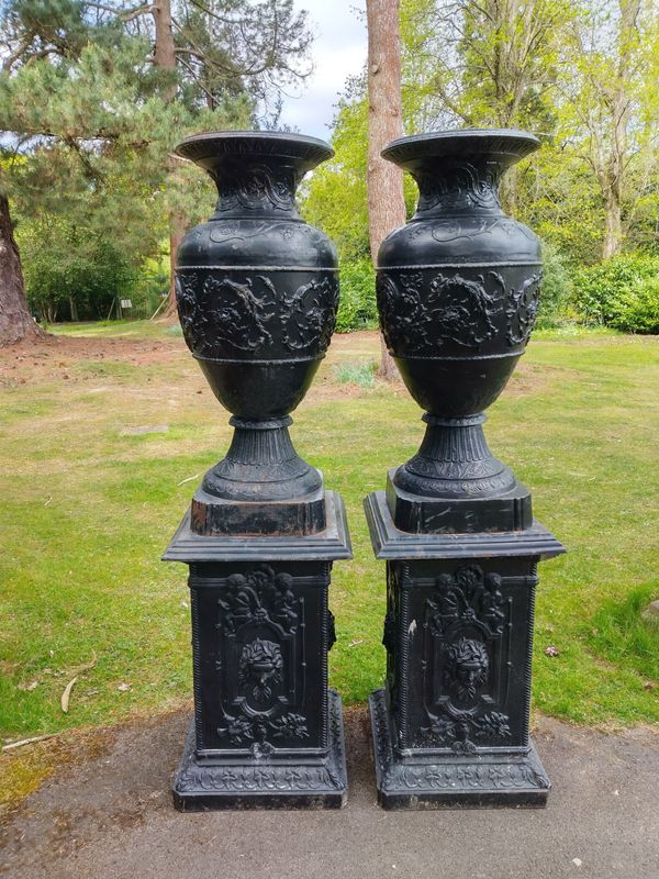 A pair of  substantial cast iron urns on pedestals