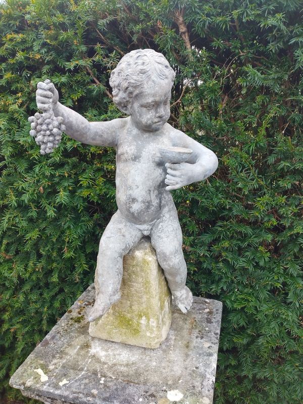 A lead figure of a putto holding a bunch of grapes